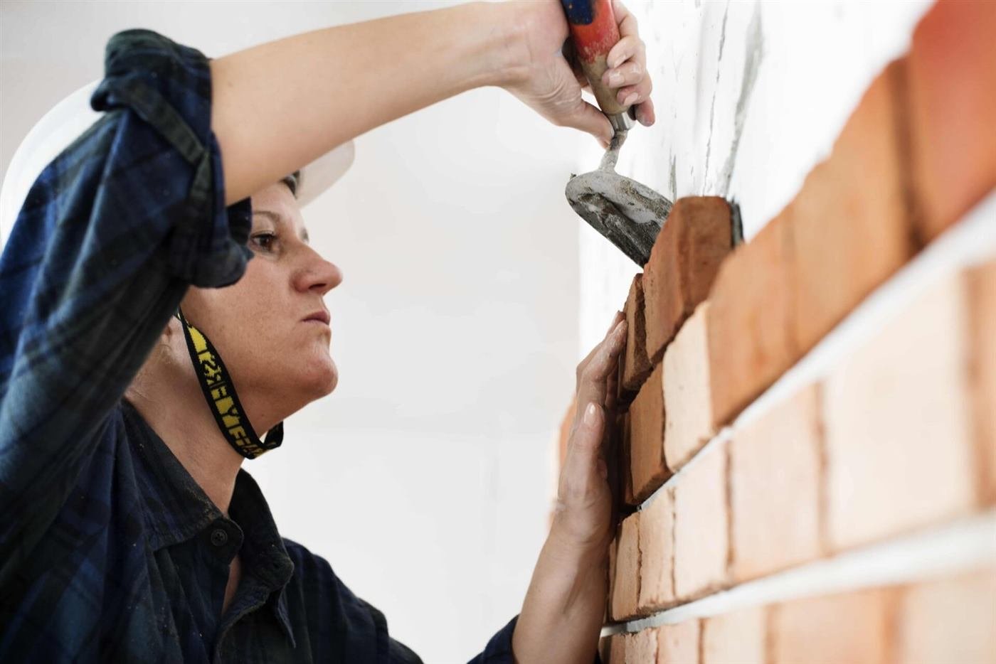 Mason laying brick with a trowel on a wall